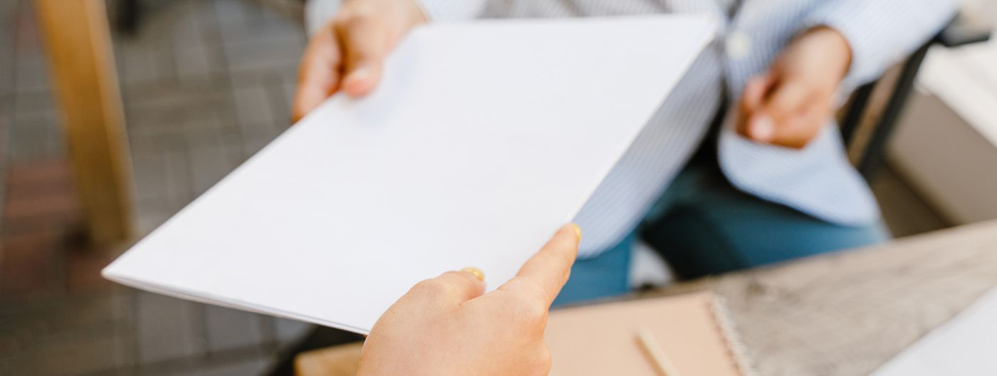 A person hands another person a piece of paper