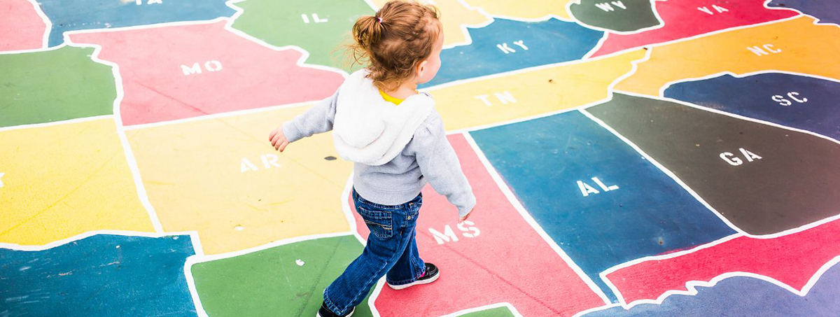 Child walking across a map of the U.S. painted on a playground